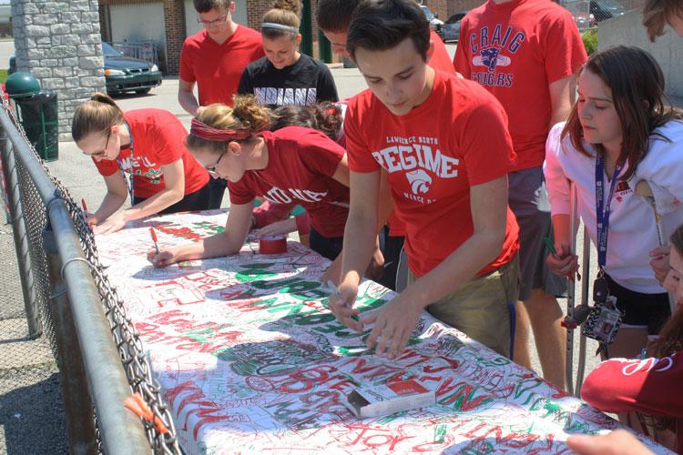 Seniors Emily Flandermeyer, Allie Henry, Nolan Cardenas and Baily Pattison sign the senior banner before entering into the Pass the Class festivities on Friday, May 1 at the LN football stadium. Pass the Class is an annual event that occurs at the end of each school year between the junior and senior classes which signifies the initiation of a new senior class.  