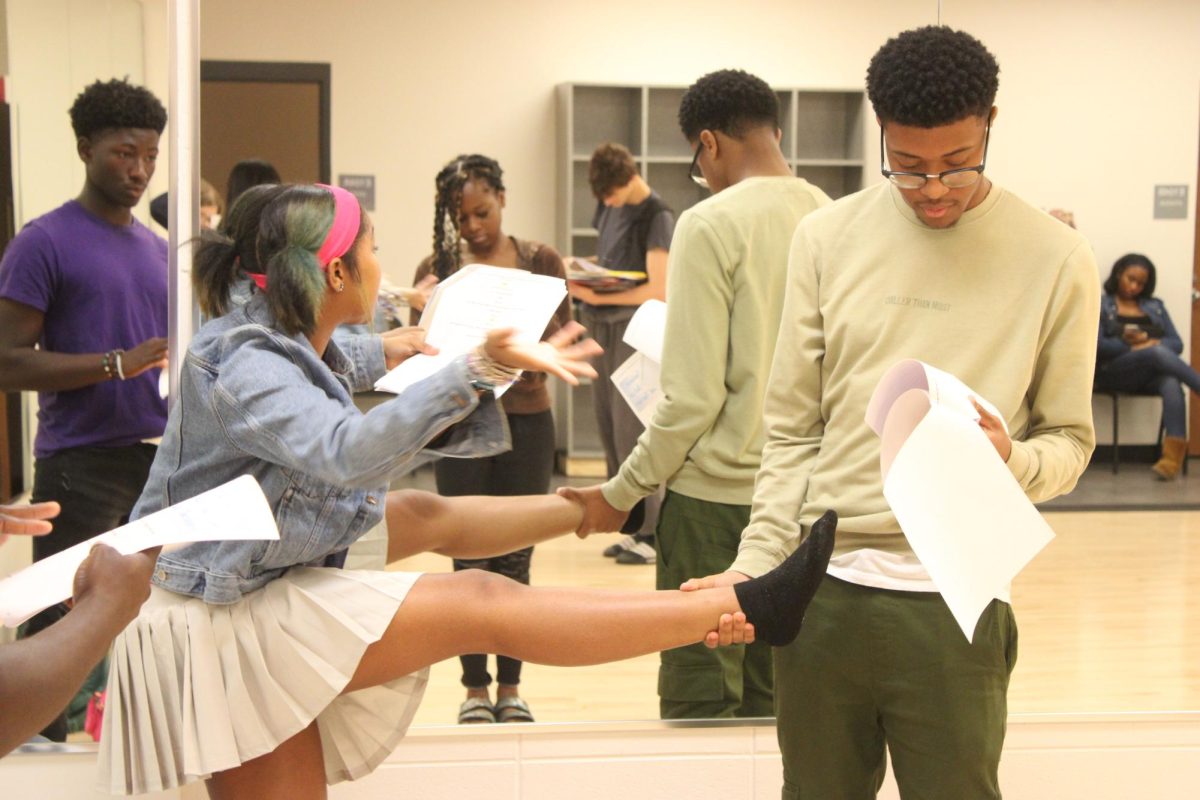 Senior Christian Dotson holds sophomore Kai Welch's foot while their group practices their roles in the skit they are rehearsing in R6 theater class.